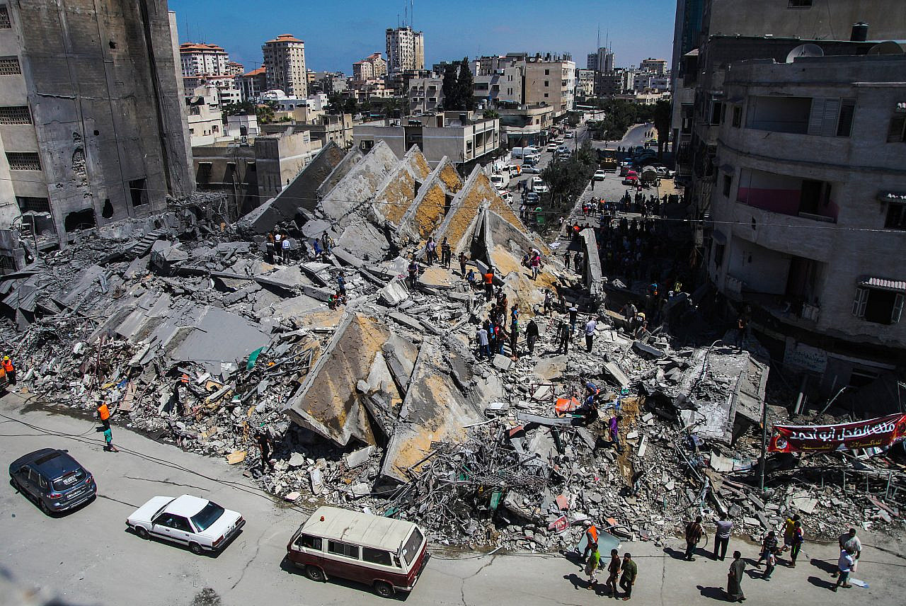 Palestinians gather around the remains of a tower building housing offices