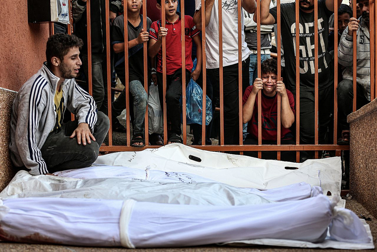 Palestinians gather around the remains of a tower building housing offices