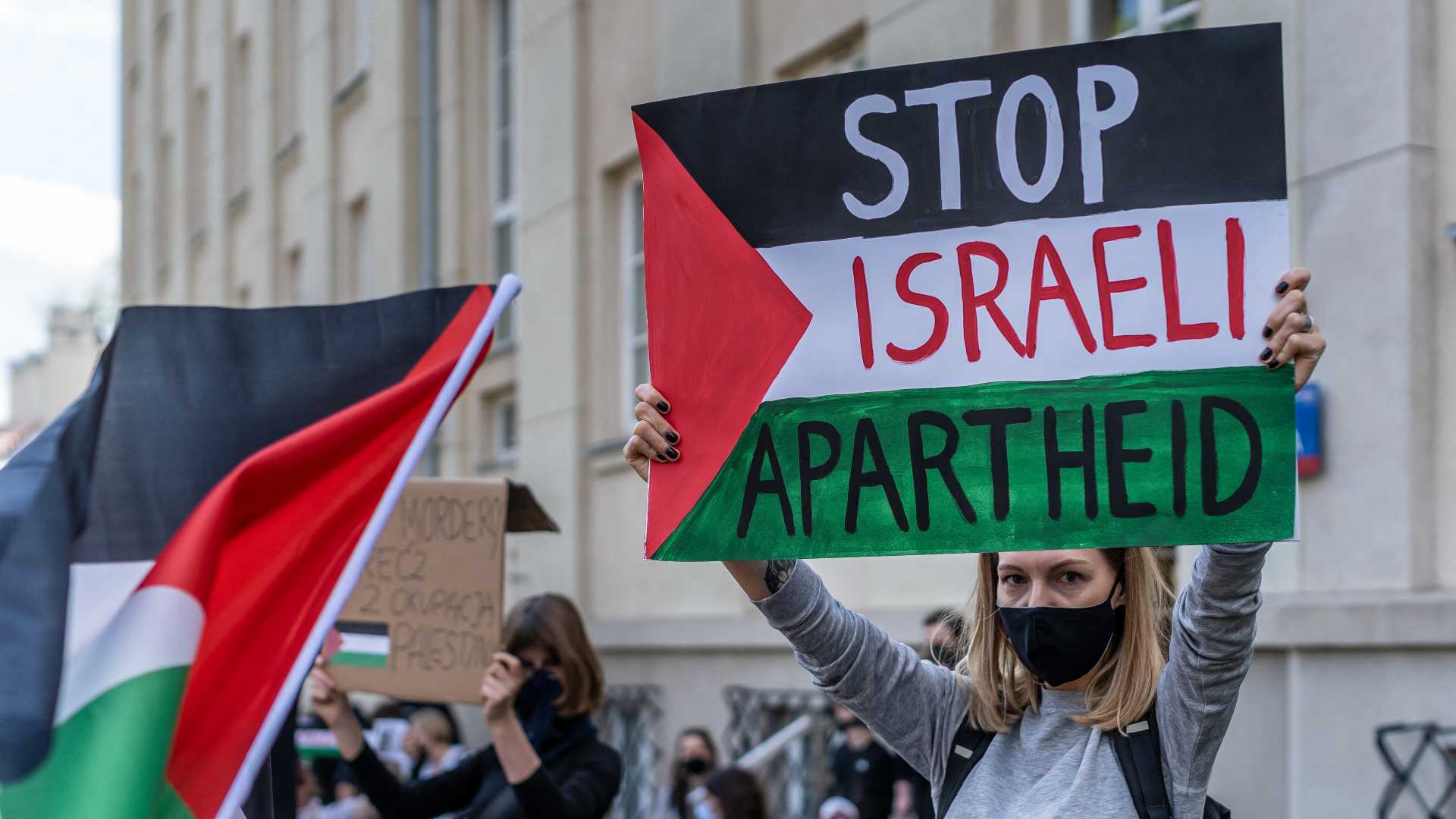 A woman holds up a sign reading 'Stop Israeli Apartheid'